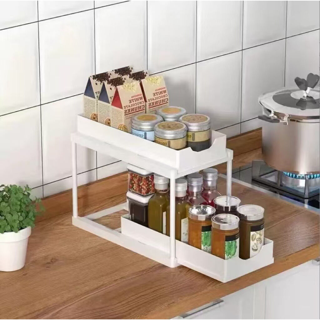 Two-tier pull-out storage rack. An organizational lifesaver for under the kitchen sink. Features adjustable shelves for easy storage of bottles and jars. In a sleek, modern design. Perfect as a kitchen shelf, bathroom organizer, or household storage solut